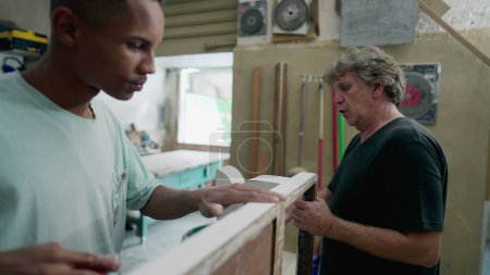 Photo for Carpenters working at workshop. Senior and young employee polishing wooden furniture, authentic Brazilian small business in South America - Royalty Free Image