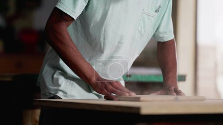 Téléchargez les photos : Young Brazilian Carpenter Trimming Wood at Workshop Close-Up View. Jeune travailleur concentré Découpage du bois à l'atelier de menuiserie - en image libre de droit