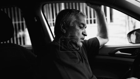 Photo for Lonely Older Person in Desperate Dire Circumstances, Struggling in Quiet Despair Inside Parked Car, dramatic monochromatic, black and white - Royalty Free Image