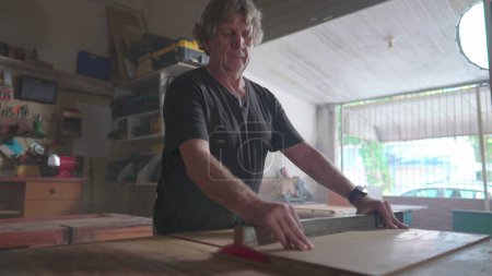 Téléchargez les photos : Maître charpentier travaillant dans un atelier de menuiserie, tranchant du bois avec une scie. Artisanat artisanal au magasin local, atelier de bois - en image libre de droit