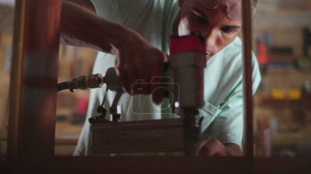 Foto de Un joven empleado negro de la carpintería concentrado usando equipo de perforación en el taller - Imagen libre de derechos