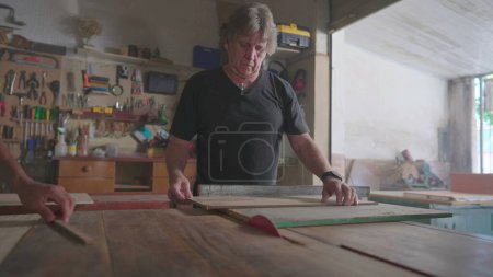Photo for Master carpenter working at carpentry workship, slicing piece of wood with saw machine. Artisan craftmanship at local shop, wood workshop - Royalty Free Image