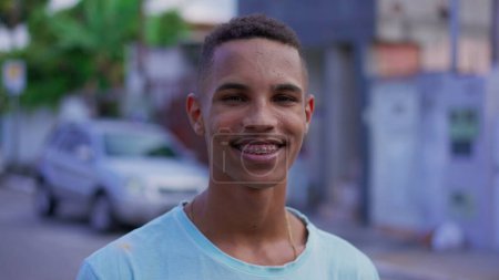 Téléchargez les photos : Portrait d'un jeune Sud-Américain noir souriant à la caméra, visage en gros plan d'un Brésilien joyeux et joyeux avec des bretelles - en image libre de droit