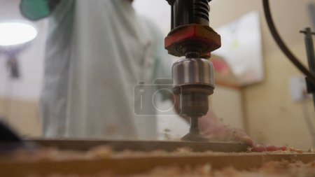 Photo for Close-up of drilling machine making a hole into wooden surface in slow-motion. Industrial equipment at carpentry workshop - Royalty Free Image