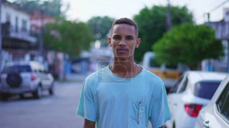 Téléchargez les photos : Un cher jeune Brésilien noir marchant dehors dans la rue avec un regard contemplatif. Une personne sud-américaine réfléchie qui avance en mouvement - en image libre de droit