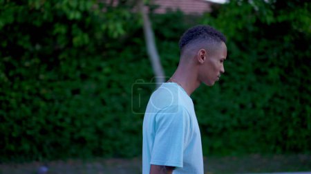 Téléchargez les photos : Un Brésilien Noir marchant dans la rue avec une expression contemplative réfléchie, réfléchissant profondément à une décision difficile - en image libre de droit