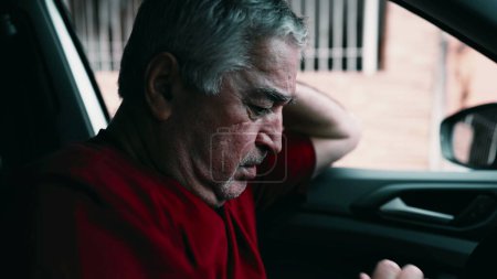 Foto de Hombre mayor sufriendo dolor emocional dentro del coche, estacionado en la calle. Dramático anciano solitario en circunstancias desesperadas, luchando en la desesperación tranquila, socialmente desconectado - Imagen libre de derechos