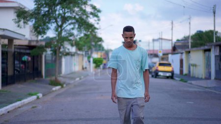 Téléchargez les photos : Un Brésilien Noir marchant dans la rue avec une expression contemplative réfléchie, réfléchissant profondément à une décision difficile - en image libre de droit