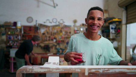 Foto de Retrato de un alegre empleado brasileño de negocios locales sonriendo a la cámara de pie dentro de un taller dedicado a la ocupación laboral - Imagen libre de derechos