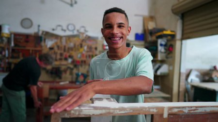 Téléchargez les photos : Portrait d'un employé brésilien joyeux d'une entreprise locale souriant à la caméra debout à l'intérieur de l'atelier engagé dans la profession - en image libre de droit