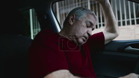 Foto de Hombre mayor arrepentido sintiendo vergüenza y culpa, recordando trauma del pasado, luchando solo dentro del coche estacionado inclinado hacia adelante sosteniéndose en el volante - Imagen libre de derechos