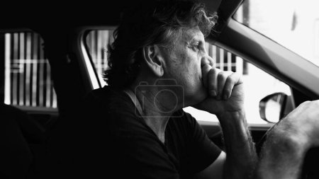 Photo for Senior Man Experiencing Sadness in Parked Car, Holding Steering Wheel, Struggling with Depression, dramatic black and white - Royalty Free Image