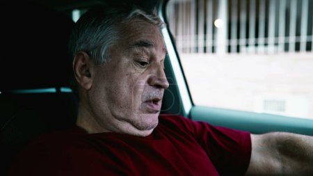 Photo for Senior man suffering from emotional despair parked in car, older person leaning face on vehicle's steering wheel in quiet despair and social disconnection. Vulnerable anxious older person - Royalty Free Image