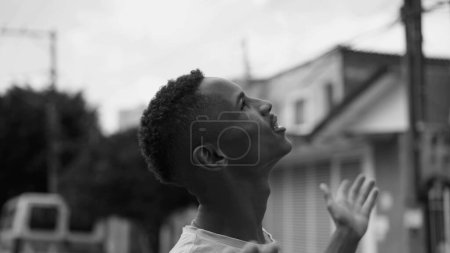 Téléchargez les photos : Un fidèle Afro-Américain levant les yeux vers le ciel avec HOPE. Jeune joyeux souriant regardant vers le haut en noir et blanc monochromatique - en image libre de droit