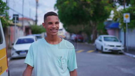 Foto de Un joven brasileño alegre saludando a su vecino caminando por la calle. Feliz saludo individual sudamericano amigo con la mano - Imagen libre de derechos