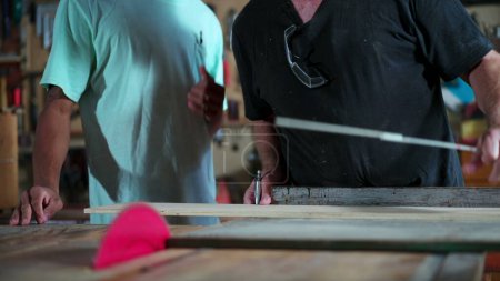 Foto de Carpinteros midiendo longitud de madera con pluma y regla en taller de carpintería, personas dedicadas a su profesión, trabajo en la industria - Imagen libre de derechos