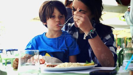 Photo for Mother Feeding Child in Restaurant, Candid Family Meal During Vacation, Child on Mom's Lap - Royalty Free Image