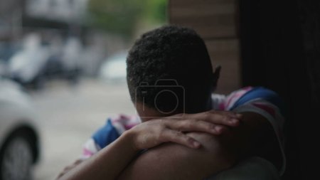 Photo for One depressed young black man struggles with social isolation and mental illness, covering face in shame and regret. Person of African American descent facing quiet despair - Royalty Free Image