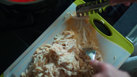Foto de Trituración a mano de pollo con tenedor en vista de cerca, separando piezas de pollo con tenedor para la preparación de la comida - Imagen libre de derechos