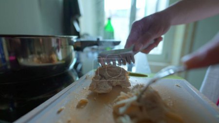 Téléchargez les photos : Gros plan / main séparant morceaux de poulet avec fourchette pour la préparation des repas - en image libre de droit