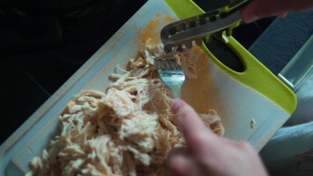 Foto de Trituración a mano de pollo con tenedor en vista de cerca, separando piezas de pollo con tenedor para la preparación de la comida - Imagen libre de derechos