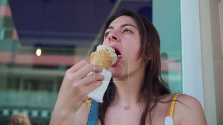 Téléchargez les photos : Femme dégustant un cône de crème glacée pendant la journée d'été. 30s femme absorbé par doux dessert - en image libre de droit