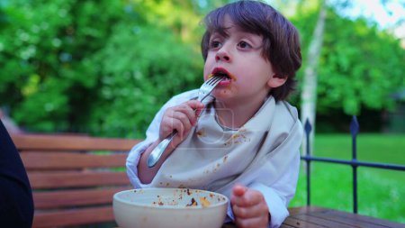Photo for Outdoor Pasta Feast, Boy eating Noodles, Collar Shielded by Napkin - Royalty Free Image