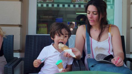 Téléchargez les photos : Mère partage cône de crème glacée à son fils pour qu'il essaie un goût différent. Parent et enfant savourant des gâteries sucrées, savourant des desserts alimentaires d'été - en image libre de droit