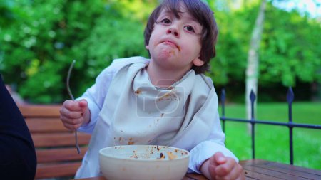 Foto de Fiesta de pasta al aire libre, Niño comiendo fideos, Cuello blindado por la servilleta - Imagen libre de derechos