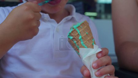 Téléchargez les photos : Mains d'enfant tenant un cône de crème glacée bleu, enfant mangeant un dessert sucré - en image libre de droit