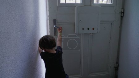 Photo for Child opening apartment front door and stepping out. Little boy open home entrance, going out to the street sidewalk - Royalty Free Image