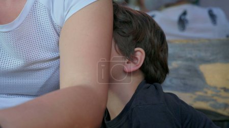 Foto de Niño aburrido escondido detrás del brazo de la madre sintiendo aburrimiento, primer plano de niño tímido sin nada que hacer - Imagen libre de derechos
