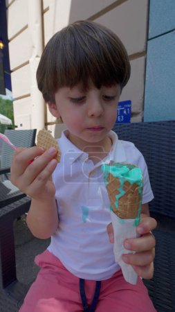 Foto de Pequeño niño disfruta de helado vibrante cono de gofre en el día soleado - Imagen libre de derechos