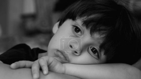 Photo for Melancholic child with sad expression, small boy struggling with depression in monochrome, black and white. Dramatic portrait feeling boredom - Royalty Free Image