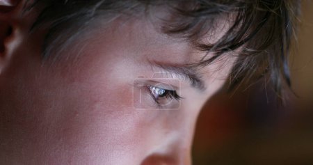 Photo for Boy eyes looking at device screen. Child staring at bright blue display closeup face - Royalty Free Image