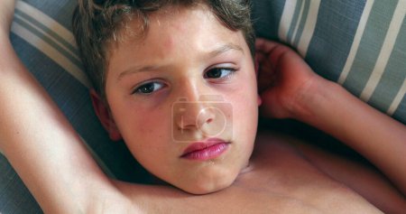 Photo for Bored child boy lying at sofa at home - Royalty Free Image