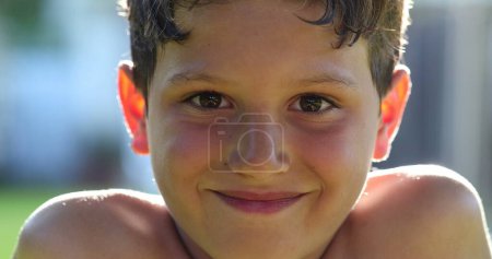 Téléchargez les photos : Garçon enfant souriant à la caméra portrait visage à l'extérieur au parc - en image libre de droit