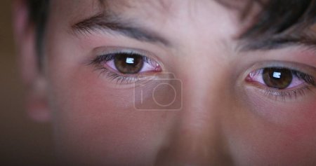 Foto de Boy eyes looking at screen device, blue light glowing from tablet screen. Child macro eye - Imagen libre de derechos