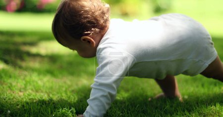 Téléchargez les photos : Adorable bébé apprenant à marcher et à se tenir dehors dans la nature. Nourrisson en équilibre - en image libre de droit