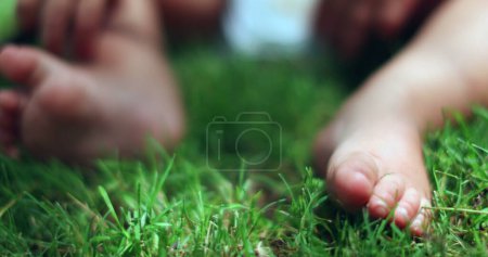 Téléchargez les photos : Bébé orteils et les pieds sur l'herbe à l'extérieur dans la nature. Jambes de bambin mise à la terre - en image libre de droit