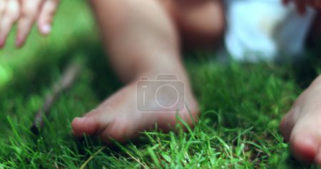 Téléchargez les photos : Bébé orteils et les pieds sur l'herbe à l'extérieur dans la nature. Jambes de bambin mise à la terre - en image libre de droit