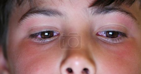 Foto de Boy eyes macro close-up watching content online. Child staring at blue light device screen - Imagen libre de derechos