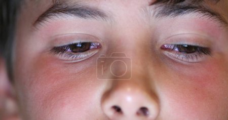 Téléchargez les photos : Boy eyes macro close-up watching content online. Child staring at blue light device screen - en image libre de droit