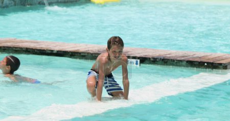 Foto de Familia cándida en la piscina disfrutando de las vacaciones de verano. Niño saltando al agua de la piscina - Imagen libre de derechos