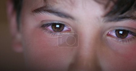 Foto de Boy eyes looking at screen device, blue light glowing from tablet screen. Child macro eye - Imagen libre de derechos