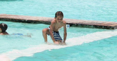 Téléchargez les photos : Famille franche à la piscine profitant de vacances d'été. Enfant sautant dans l'eau de la piscine - en image libre de droit
