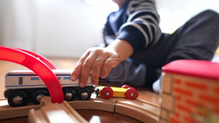 Téléchargez les photos : Gros plan enfant jouant avec des jouets traditionnels sur des rails de train en bois. Petit garçon pousse wagon rétro - en image libre de droit