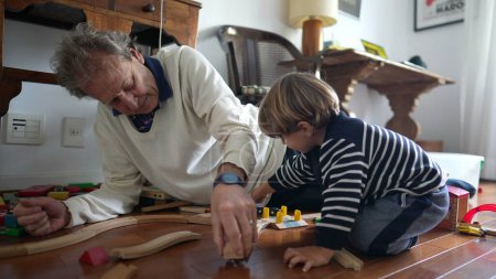 Photo for Elderly Man and Young Boy Building Train Set on Wooden Floor, grandfather and child grandson bonding time together - Royalty Free Image