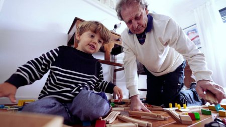 Photo for Authentic Moment Between Elderly Man and Grandchild Playing, building train tracks. Grandfather and Grandson Bonding on Bedroom Floor - Royalty Free Image