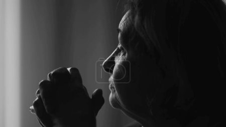 Téléchargez les photos : Femme âgée monochromatique profondément absorbée par la pensée, gros plan montrant son intention de se concentrer alors qu'elle se penche vers l'avant à la recherche de réponses, noir et blanc - en image libre de droit